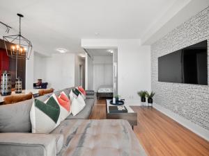 Stylish One Bedroom Suite - Entertainment District Toronto في تورونتو: غرفة معيشة مع أريكة وتلفزيون