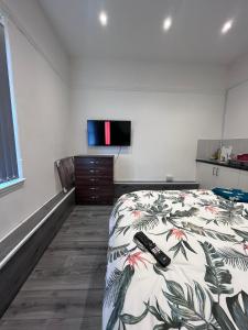 a bedroom with a bed with two remote controls on it at Studio Flat with Kitchenette in Birmingham