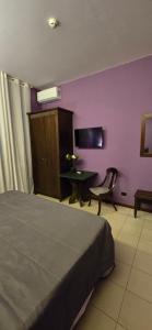 una camera con letto, scrivania e parete viola di Smart Station Hotel a Napoli