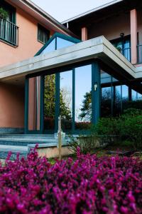 un bâtiment avec des fleurs violettes devant lui dans l'établissement Hotel Villa Delle Rose - Malpensa, à Oleggio