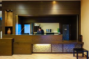 a man sitting at a desk in a room with a mirror at Hotel Villa Delle Rose - Malpensa in Oleggio