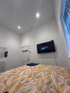a bedroom with a bed with a flat screen tv on the wall at Snugly Studio Flat near Talbot Pub in Birmingham