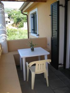 a white table and chair on a balcony with a window at Gioiosa Marea Appartamento per 4 con vista sulle Eolie Casa Spisidda "Panarea" in Gioiosa Marea