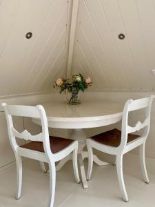 een witte tafel met twee stoelen en een vaas met bloemen bij 't Heerenhuys in Wageningen