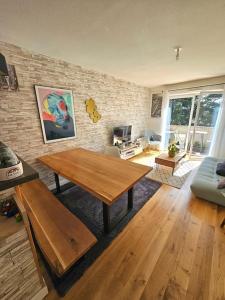 a living room with a wooden table and a brick wall at L'hippique - Parking - vue Pyrénées - Balcon in Pau