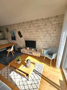 a living room with a brick wall and a tv at L'hippique - Parking - vue Pyrénées - Balcon in Pau