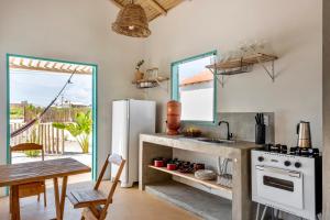 a kitchen with a white refrigerator and a table at Vila da Falésia in Corumbau