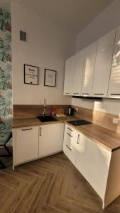 a kitchen with white cabinets and a wooden floor at APARTAMENT JARACZA 28/12 in Słupsk
