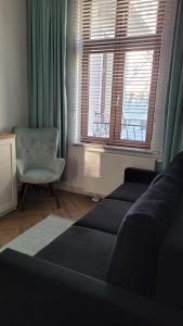 a living room with a couch and a chair and a window at APARTAMENT JARACZA 28/12 in Słupsk