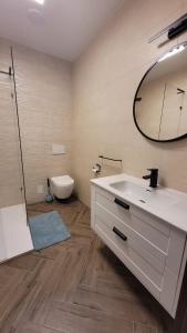 a bathroom with a sink and a toilet and a mirror at APARTAMENT JARACZA 28/12 in Słupsk