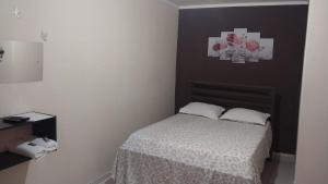 a small bedroom with a bed with two pillows at Pousada Beija flor in Extrema