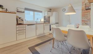 a kitchen with white cabinets and a table and chairs at Lovely Apartment / 10 min walk from city centre in Tórshavn +12 photos