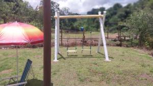 a swing set with an umbrella in a field at Pousada Beija flor in Extrema