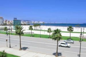 a street with cars and palm trees and the beach at Beautiful Sea View Apartment in Tangier in Tangier