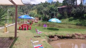 a patio with chairs and umbrellas next to a pond at Pousada Beija flor in Extrema