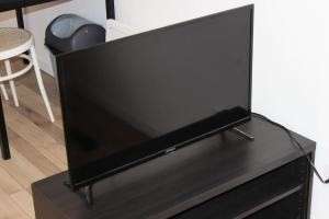 een flatscreen-tv zittend op een zwarte standaard bij Studio cosy et chaleureux in Royat