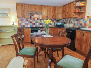 a kitchen with a wooden table with a vase of flowers at Little Barber in Reading