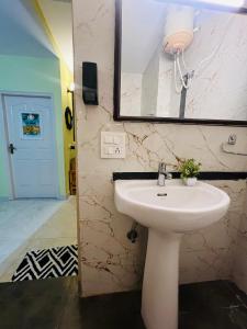 ein Badezimmer mit einem weißen Waschbecken und einem Spiegel in der Unterkunft Luna & Sol 2BHK in Kasauli