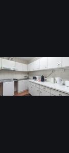 una gran cocina blanca con armarios y electrodomésticos blancos en MarinhoHouse, en Oporto
