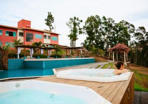 a woman in a hot tub next to a pool at Hotel Chalé Capitólio in Capitólio