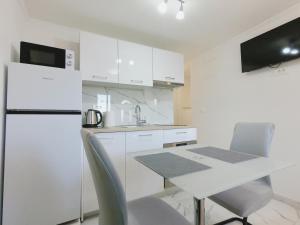 a white kitchen with a table and a refrigerator at Apartman Tina 2 in Ražanac