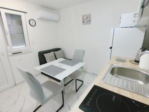a kitchen with a sink and a table and a refrigerator at Apartman Tina 2 in Ražanac