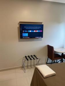 a room with a table and a tv on the wall at Excellence Plaza Hotel in Botucatu