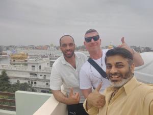 three men giving thumbs up while standing on a roof at 4N Homestay in Amritsar