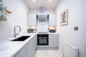 una pequeña cocina con armarios blancos y fregadero en Charming Granby Flat, en Harrogate