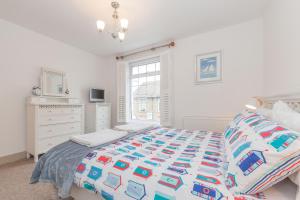 a white bedroom with a bed and a window at The Roost in Whitstable