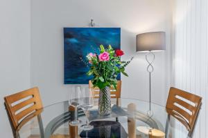 a vase of flowers on a glass table with two chairs at Extraordinary Central Flat & Roof Top Terrace in London