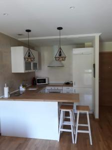 cocina con encimera y 2 taburetes en Playa y piscina a tu alcance en boiro, en Boiro