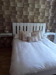 Cama blanca con almohadas en una habitación con pared de ladrillo en Playa y piscina a tu alcance en boiro, en Boiro