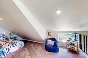 um quarto no sótão com uma cama e uma cadeira em Searose Cottage em Yachats