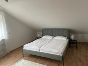a bedroom with a bed with white sheets and two tables at Dell Ferienwohnung in Offenburg
