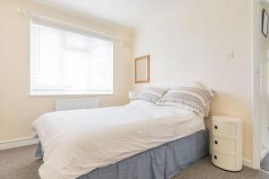 a bedroom with a bed with white sheets and a window at Tideway in Whitstable