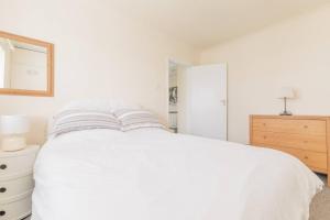 a white bedroom with a white bed and a dresser at Tideway in Whitstable