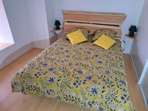 - un lit avec un couvre-lit jaune et bleu et des oreillers jaunes dans l'établissement APPARTEMENT BEAU SOLEIL, à La Bâtie-Neuve