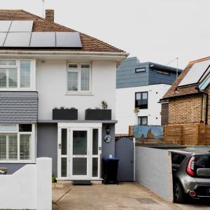 a white house with a door and a car at Tideway in Whitstable