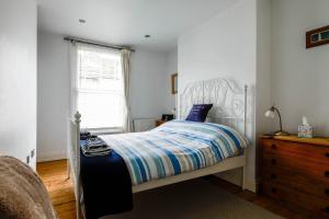 1 dormitorio con cama blanca y ventana en Victoria Cottage, en Whitstable