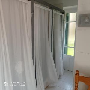 una fila de cortinas blancas en una habitación con ventana en Albergue Armaia Artepea, en Urzainqui