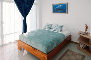 a bedroom with a bed with blue sheets and a window at Modernas Habitaciones in Puerto Ayora