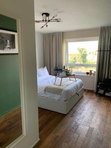 a bedroom with a bed with a table and a window at Light & Airy Oasis in South Norwood