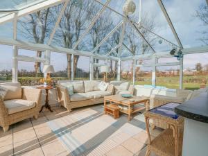 a conservatory with white furniture and glass windows at Bryn Cyttun in Pwllheli