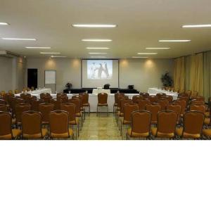 une salle de conférence avec des tables, des chaises et un écran dans l'établissement Flat Apart Bristol Hotel Goiânia - Crystal Place, à Goiânia