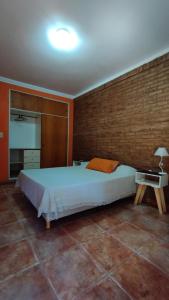 1 dormitorio con cama y pared de ladrillo en La Casa del Paraná - San Pedro en San Pedro