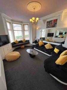 a living room with a black couch and yellow pillows at Winter Gardens large modern home in Blackpool