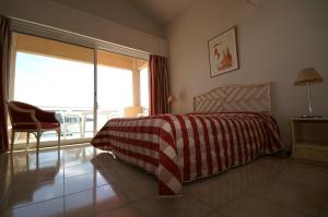 a bedroom with a bed with a red and white blanket at Hôtel La Flore in Villefranche-sur-Mer