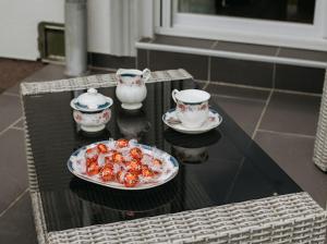 une table avec une assiette de nourriture et deux tasses à thé dans l'établissement Apartmani Mikic, à Palić