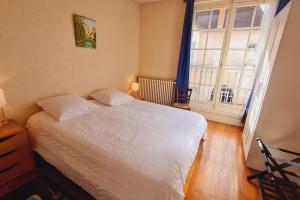 a bedroom with a white bed and a large window at Bouchardine - Centre - Parking gratuit - Hospices in Beaune